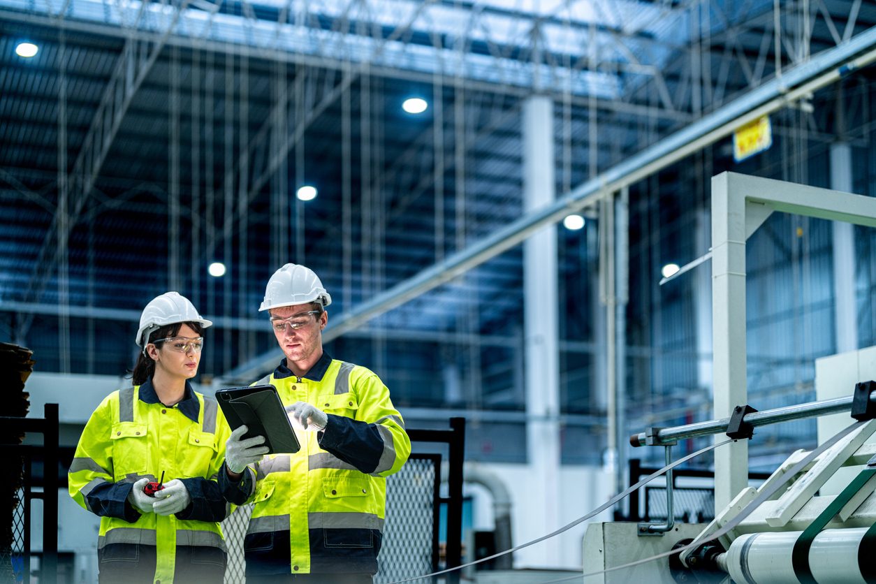 Deux travailleurs en usine consultent une tablette