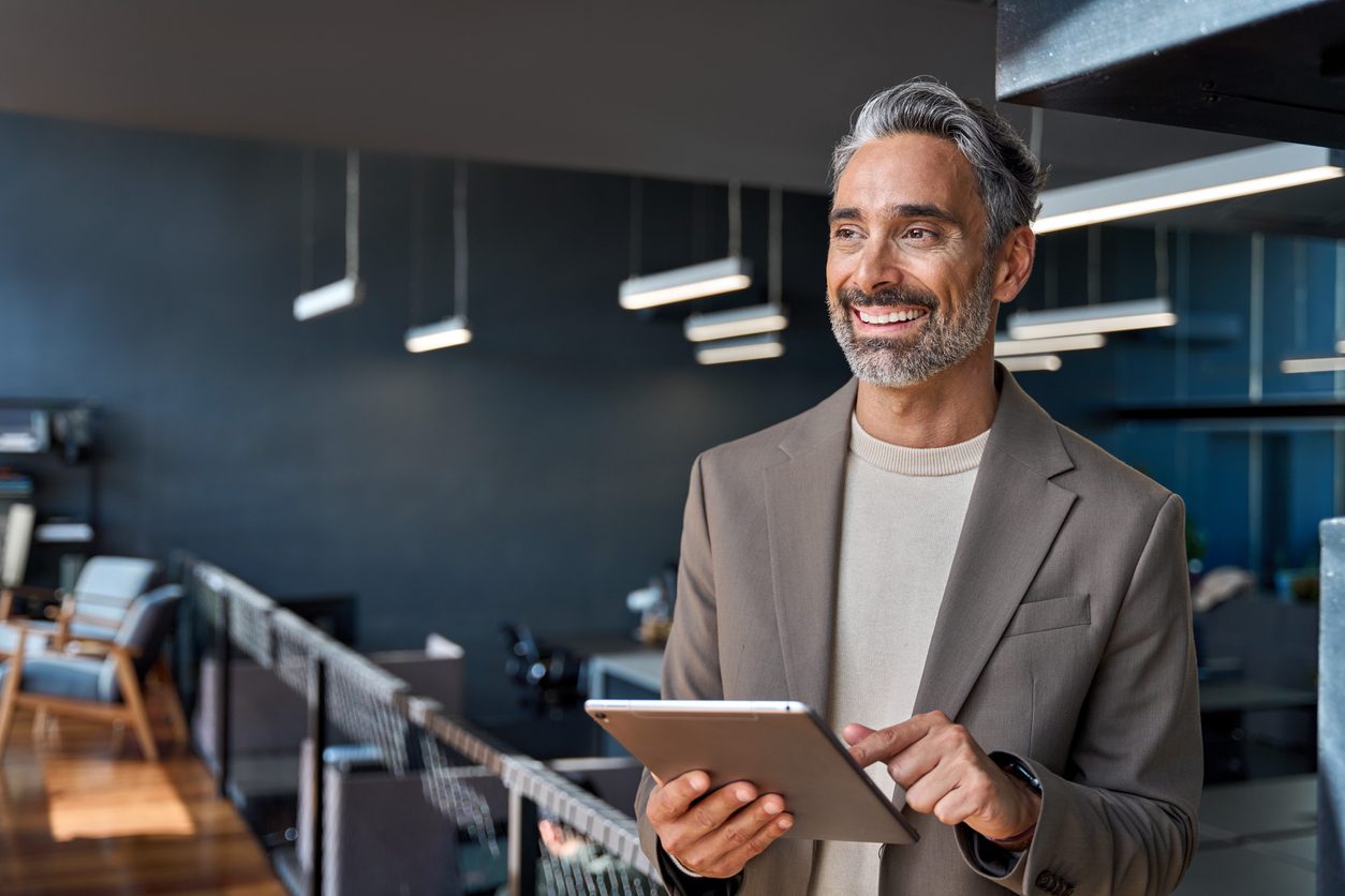 Dirigeant souriant tenant une tablette dans un bureau moderne